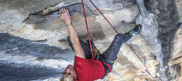 Connor Dickinson hanging from a rope climbing a limestone rockface in china