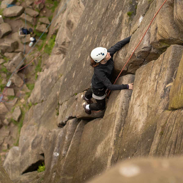 A beginner rock climber ascends a rock face at Frogatt Edge in Derbyshire