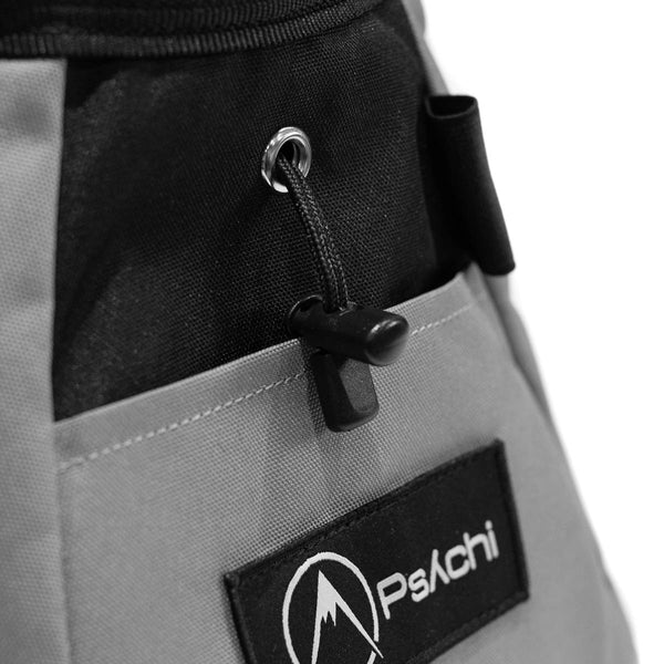 A light grey and black bouldering chalk bucket with drawstring closure and climbing accessory pockets