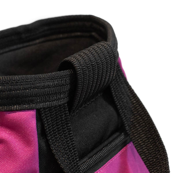 A magenta and black bouldering chalk bucket with drawstring closure and climbing accessory pockets