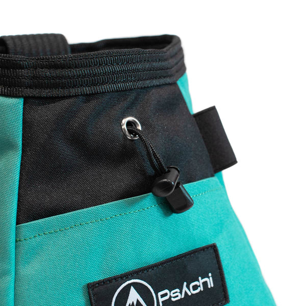 A turquoise and black bouldering chalk bucket with drawstring closure and climbing accessory pockets