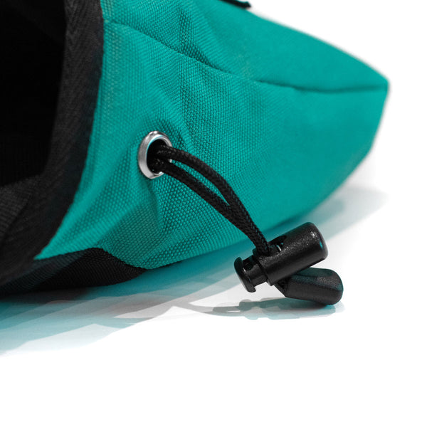 A Drawstring closure toggle on a turquoise climbing chalk bag 