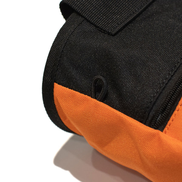 An elastic climbing brush holder on a light orange climbing chalk bag 